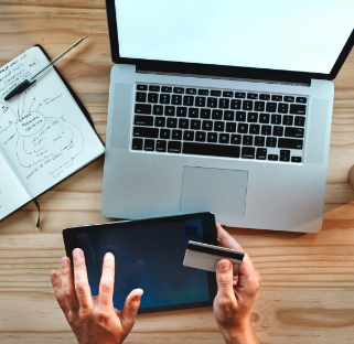 Hands holding an iPad and credit card while working at computer